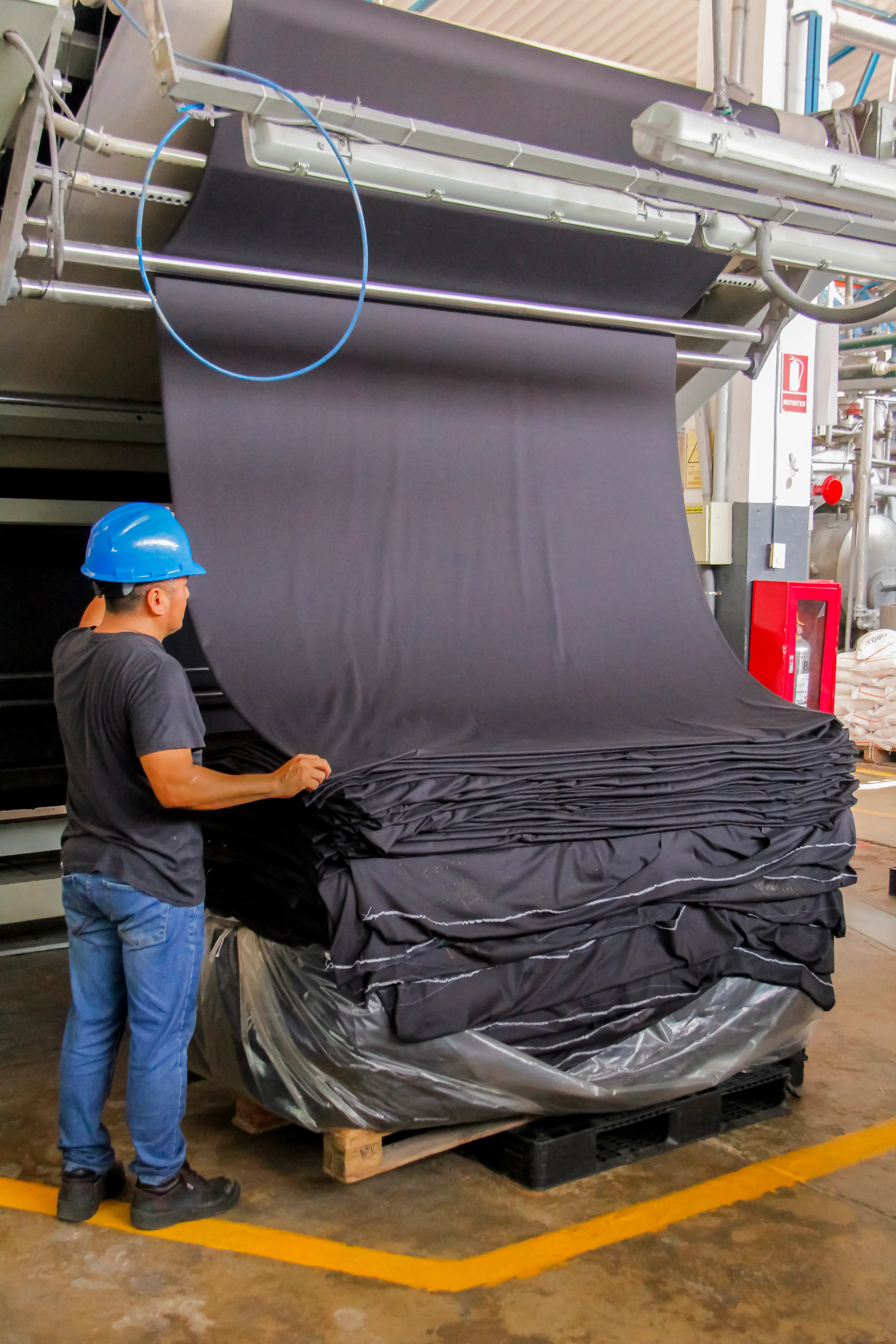Operario supervisando rollos textiles en planta